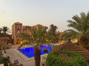 a resort with a swimming pool and palm trees at Sbai Palace in Mhamid