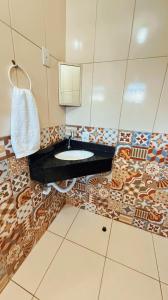 a bathroom with a sink and a mosaic tile wall at Pousada Fielder e Anacleto in Penha +23 photos