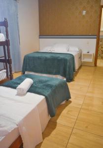 a room with two beds with green and white sheets at Pousada Fielder e Anacleto in Penha