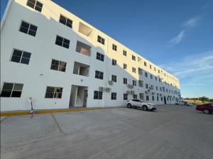 a large white building with cars parked in a parking lot at Departamento a 3 min de Playa Miramar in Ciudad Madero