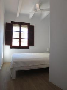 a white bedroom with a bed and a window at Casa al Castillo - charming & authentic townhouse - terrace with stunning castle views in Cullera