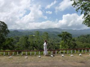 a woman standing on a fence looking at the mountains at Thanayama Deniyaya in Deniyaya