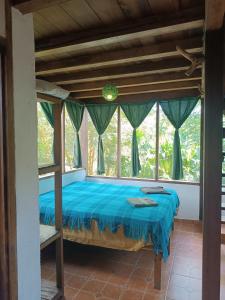 a bedroom with a bed in a room with windows at Lodge France Amazonia in Puerto Misahuallí