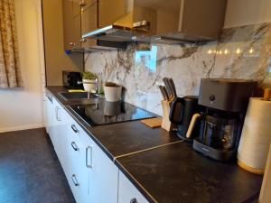 a kitchen with white cabinets and a black counter top at Bachoase Bischofsmais in Bischofsmais