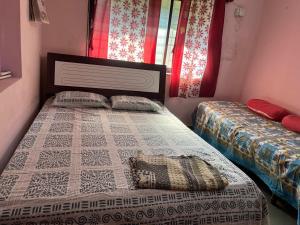 a bedroom with two beds and a window at Prakash Banglow in Malvan