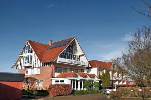 a large building with a red roof at Hotel Mellum in Wangerland