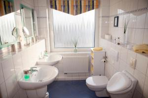 a bathroom with two sinks and a toilet and a window at Hotel Mellum in Wangerland +16 photos