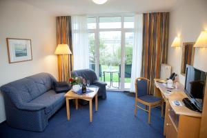 a hotel room with a couch and a table and a television at Hotel Mellum in Wangerland