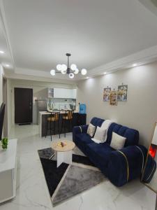 a living room with a blue couch and a kitchen at Lyon in Nairobi
