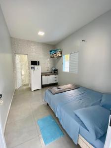 a bedroom with a blue bed and a refrigerator at -TROPICAL SUÍTES- ao lado do SESC-BERTIOGA in Bertioga