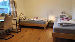 a room with two beds and a desk and a window at Bachoase Bischofsmais in Bischofsmais