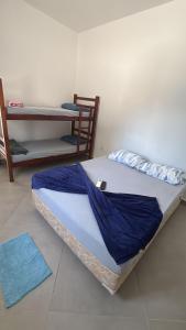 a bed with a blue comforter in a room at -TROPICAL SUÍTES- ao lado do SESC-BERTIOGA in Bertioga