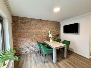 a dining room with a brick wall and a table and green chairs at Apartment Mira 13 in Pulheim