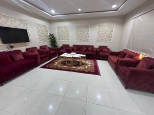 a waiting room with red couches and a flat screen tv at شاليهات تولين 2 in Taif +5 photos