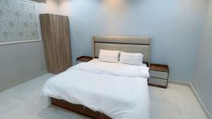 a bedroom with a white bed with two pillows at شاليهات تولين 2 in Taif