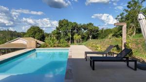 a swimming pool with two lounge chairs next to it at Ecofazenda Lodge in Bofete