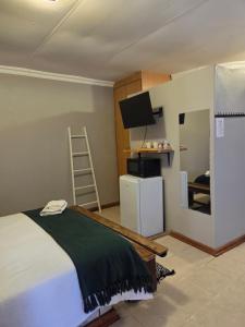 a bedroom with a bed and a tv and a refrigerator at Sunset View River Guesthouse in Douglas