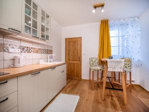 a kitchen with white cabinets and a wooden table at Apartmán Jimi Hendrix in Nymburk