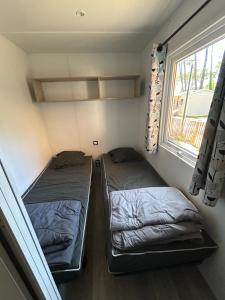 two beds in a small room with a window at Camping les Olyats in Seignosse