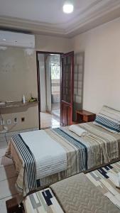 two beds in a white room with a bathroom at Casa Meão in Recife