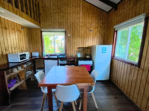 a kitchen with a wooden table and white appliances at Cabañas CyG - Chaitén in Chaitén