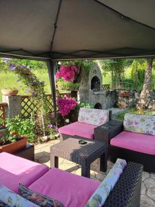 acovered patio with pink cushioned chairs and a table at Domacinstvo Majovac in Drenova