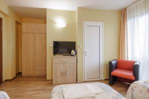 ein Zimmer mit einem Bett, einem Fernseher und einem Stuhl in der Unterkunft Trafi Em in Sofia