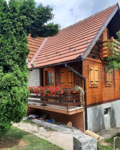 a house with a balcony with flowers on it at Domacinstvo Majovac in Drenova