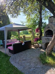 a patio with a couch and an umbrella and a stone oven at Domacinstvo Majovac in Drenova