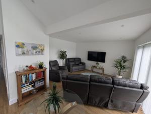 a living room with a couch and a flat screen tv at Allensmore House Gower in Swansea