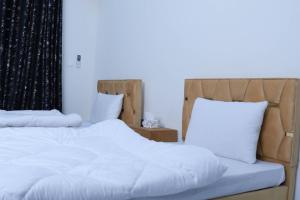 a bedroom with two beds with white sheets and pillows at Zubi Guest House in Dargai