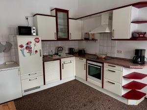 a kitchen with white cabinets and a refrigerator at Ferienwohnung Poschmann in Bad Wilsnack +6 photos