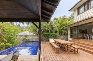 a wooden deck with a picnic table next to a swimming pool at Away Guesthouse- Away on Shirley Lane in Byron Bay