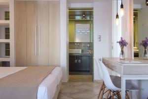 a bedroom with a bed and a desk and a kitchen at Kanale's Rooms & Suites in Naousa