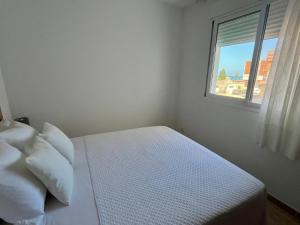 a white bedroom with a bed and a window at Casa Queralt in Les Cases d'Alcanar