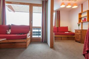 ein Wohnzimmer mit roten Möbeln und einem großen Fenster in der Unterkunft Quartier Crève Cœur - maeva Home in Valmorel