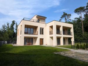 a large white house on top of a green field at Apartamenty Biwakowa 4B in Turawa
