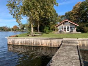 a house on the shore of a lake with a dock at Vakantiehuis - De Smidse in Haren +11 photos
