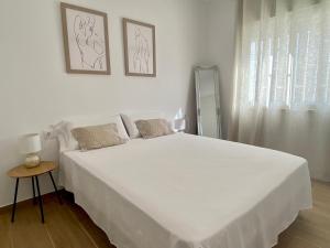 a white bedroom with a large white bed and a window at Can Blau in Les Cases d'Alcanar