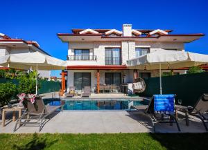 a house with a swimming pool with chairs and umbrellas at Villa Karya in Dalyan
