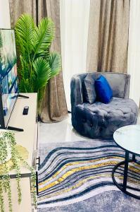 a living room with a blue chair and a rug at 7th Heaven luxury Apartment in Gaborone