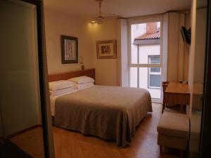 a bedroom with a bed and a window and a desk at Hotel Zarampallo in Ourense