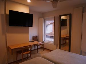 a hotel room with a desk and a television on the wall at Hotel Zarampallo in Ourense