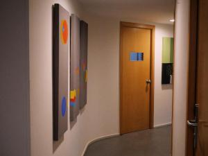 a hallway with paintings on the wall and a door at Hotel Zarampallo in Ourense