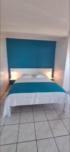 a bedroom with a bed with a blue wall at Gîtes Dardanelle in Bouillante