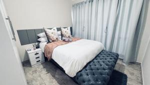 a bedroom with a large bed with a black ottoman at Casa Tranquila Luxe in Pretoria