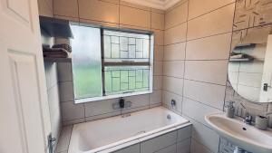 a bathroom with a tub and a sink and a window at Casa Tranquila Luxe in Pretoria +12 photos