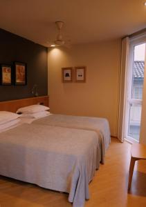 a bedroom with two beds and a window at Hotel Zarampallo in Ourense +26 photos