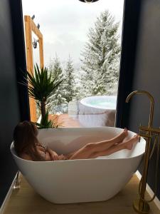 a woman laying in a bath tub in a window at Veya Cabins Apuseni in Trifeşti +31 photos