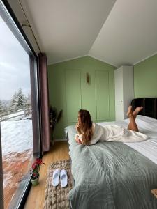 a woman laying on a bed in a bedroom at Veya Cabins Apuseni in Trifeşti